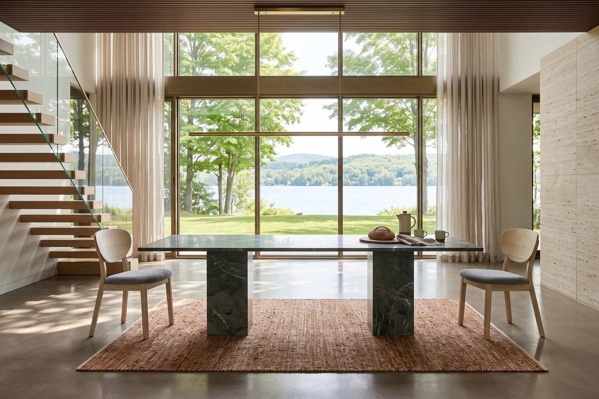 Two Rivello dining chairs at the ends of a dark green marble table in a North Hatley house