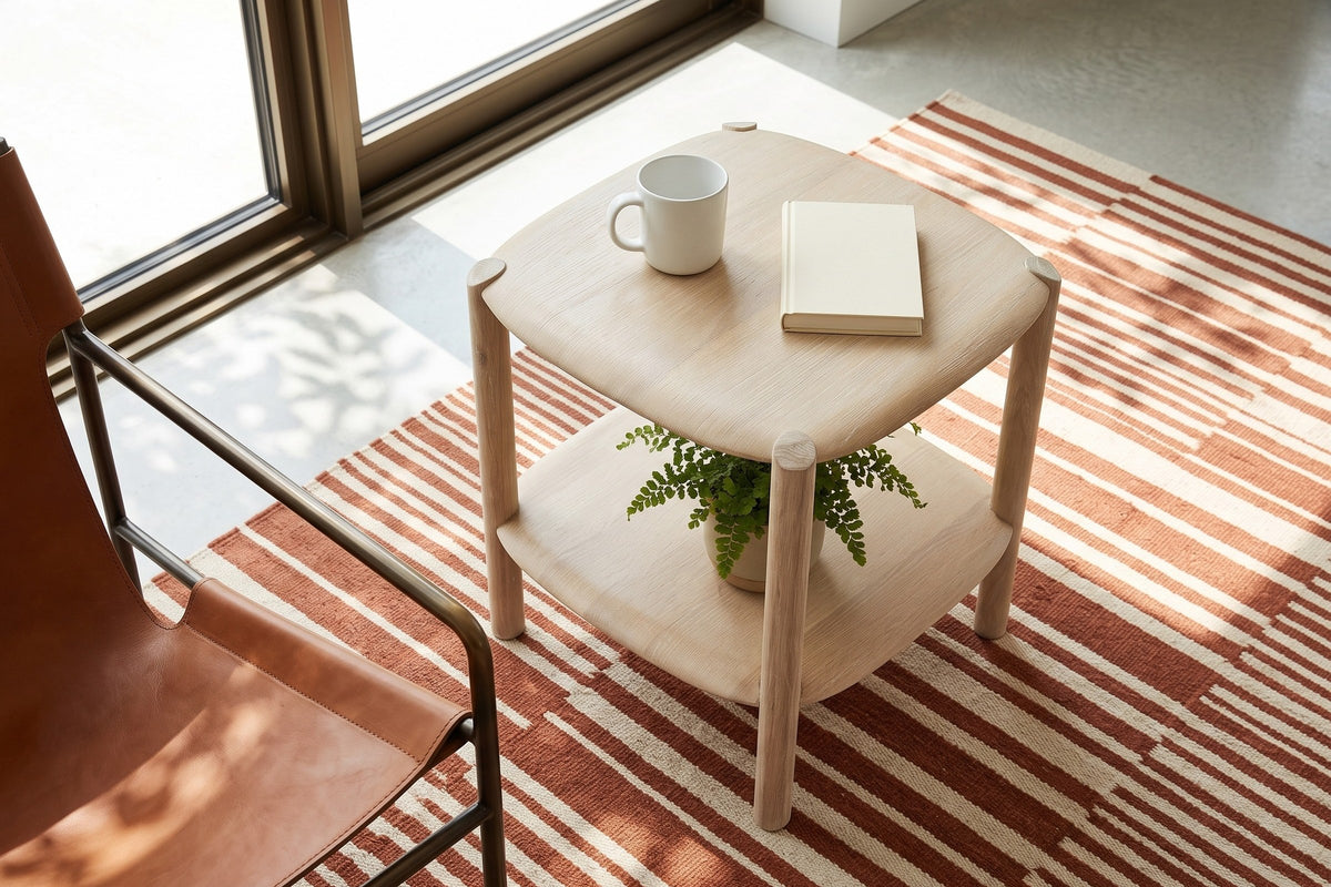 Rivello side table in Light Oak seen from above beside a cognac leather sling chair in a Lac-Beauport house