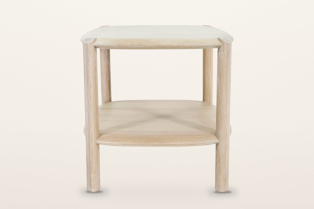 Rivello side table in Light Oak from the front, on a warm white studio backdrop: the top, the lower shelf and two round legs