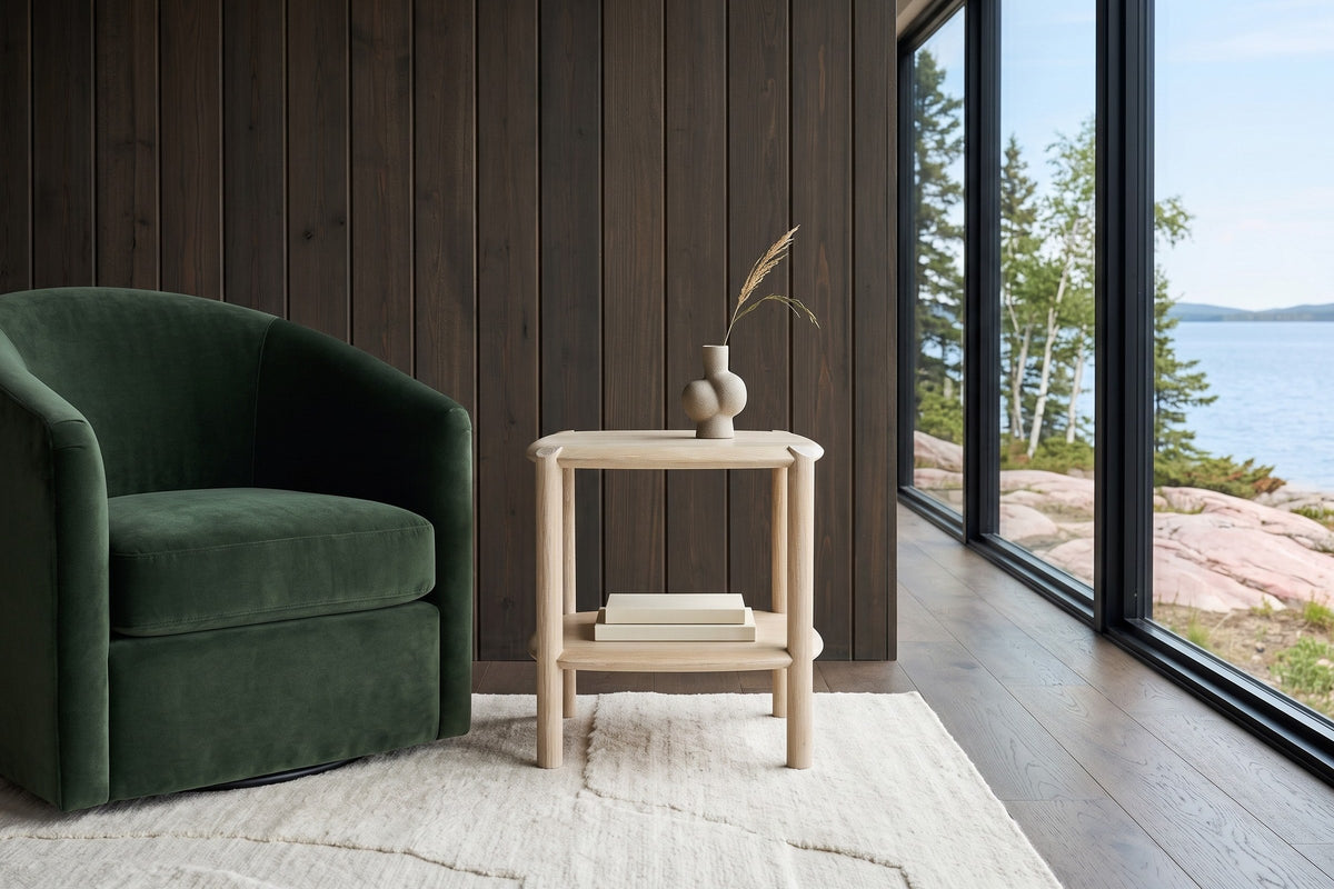 Front view of the Rivello side table in Light Oak beside a forest green velvet swivel chair in a Yellowknife house