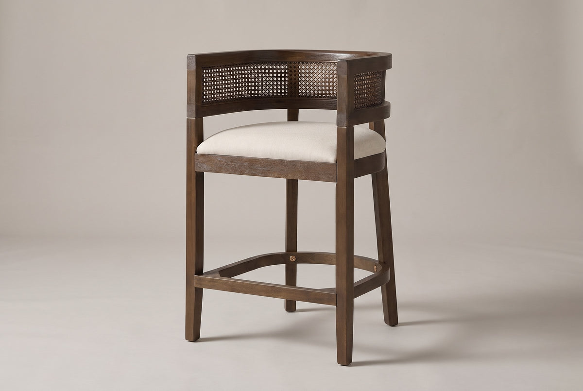 Sabaudia cane-back counter stool in Walnut, three-quarter view on a warm light-grey studio backdrop