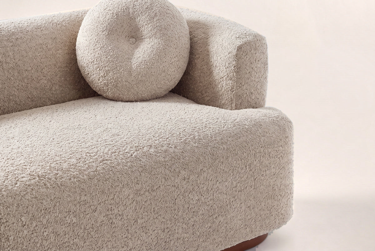 Close-up of the Almond boucle bench seat, a round button pillow and the block arm
