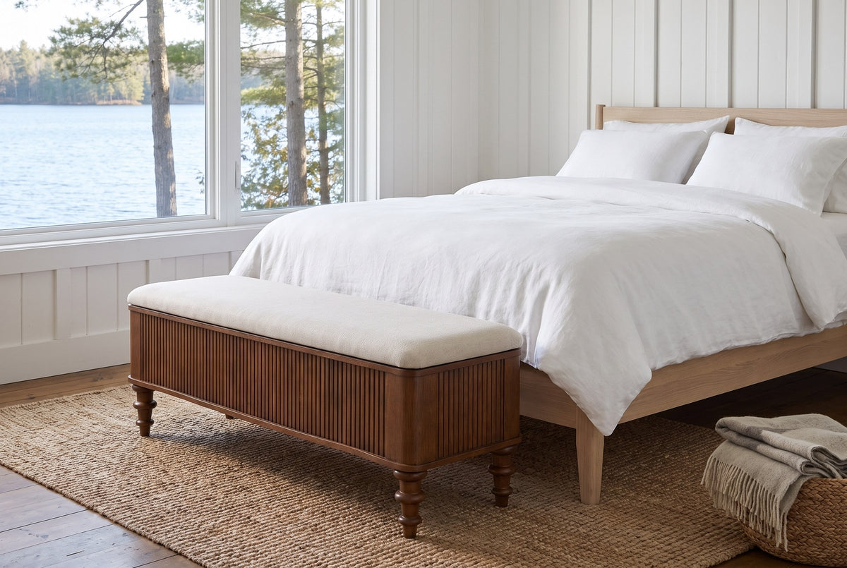 Salerno storage bench at the foot of a bed in a white board-and-batten Muskoka cottage bedroom with a lake view