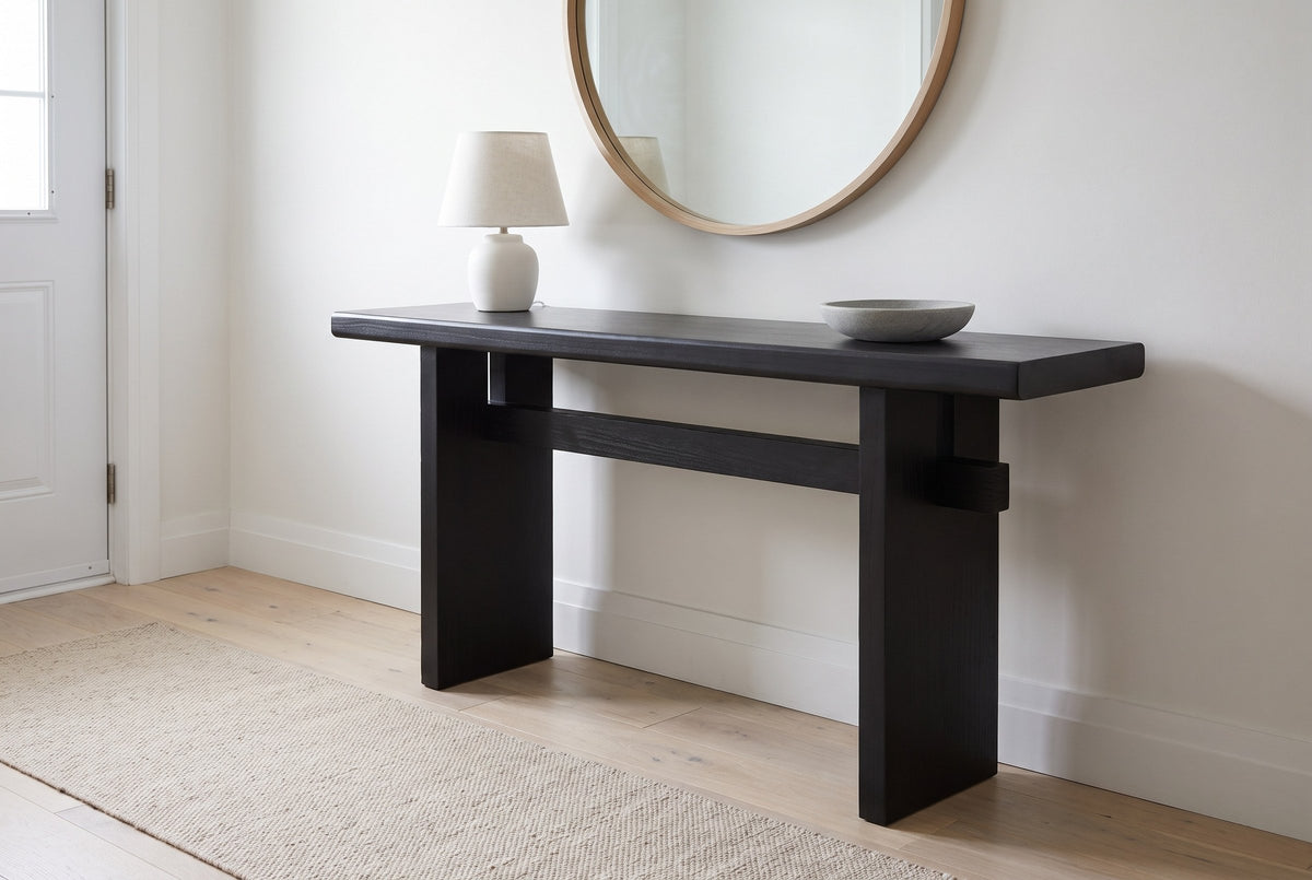 Sanremo console table in black in a white front hall under a round oak mirror, a ceramic lamp and a stone bowl on top