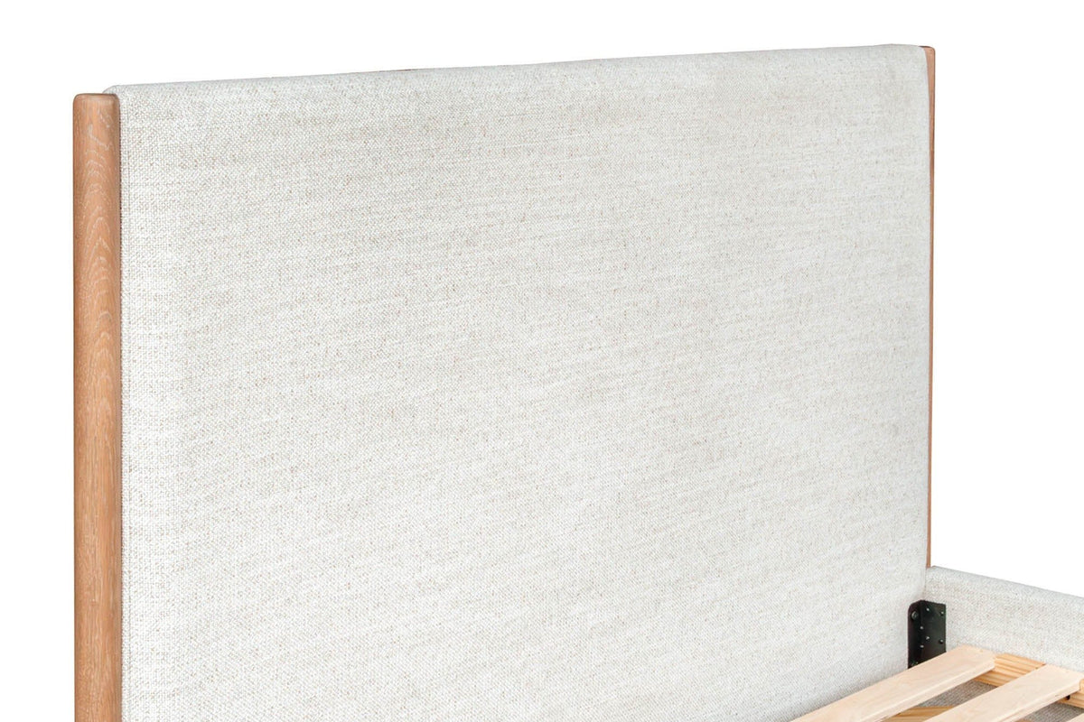 Close-up of the Sarnano headboard: the plain Alabaster upholstered panel and the round oak post at its side