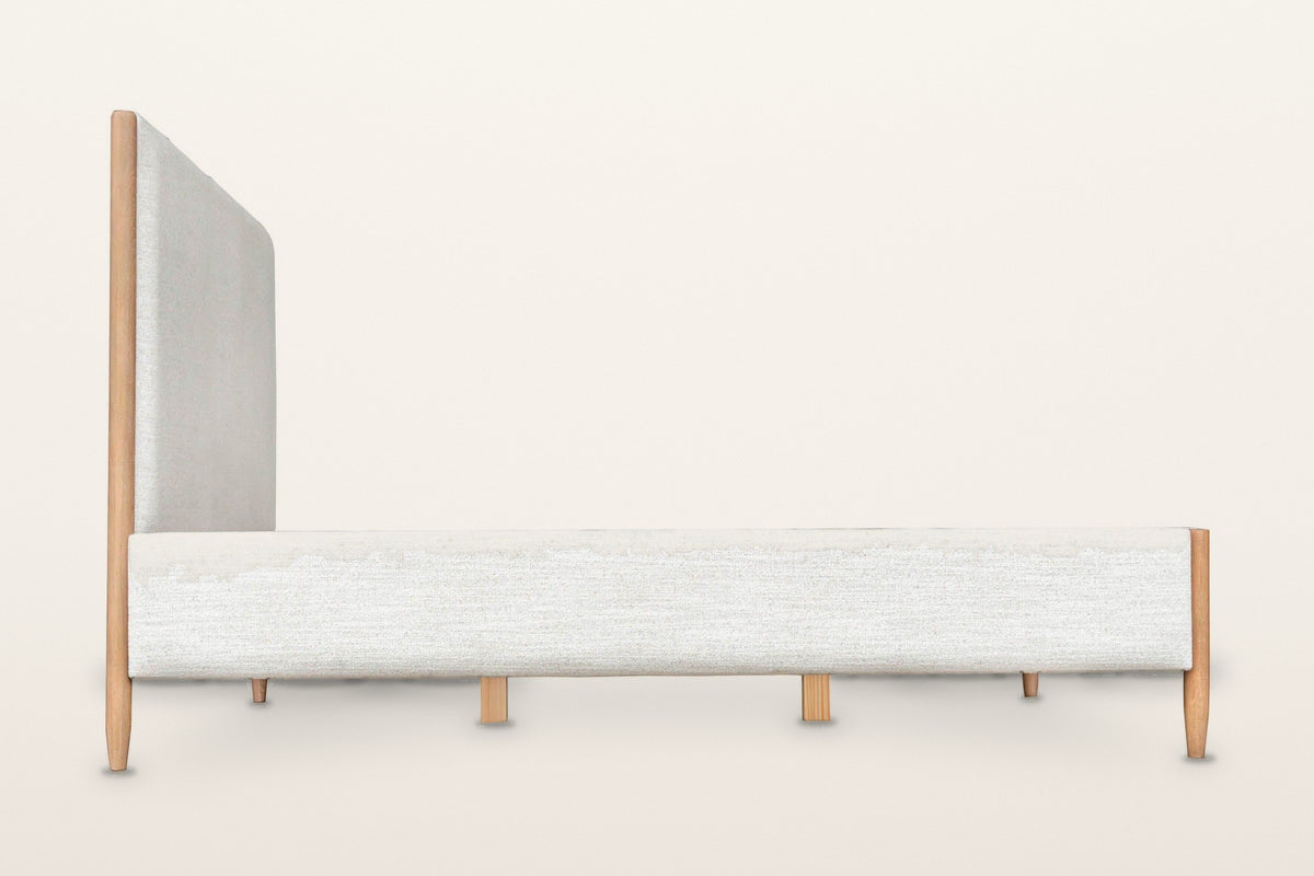 Side view of the Sarnano bed on a warm white studio backdrop: the long upholstered rail