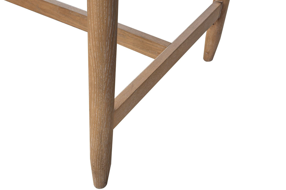 Close-up of a Sarnano leg in Sand: a round oak leg tapering to a soft foot, the low stretcher behind it
