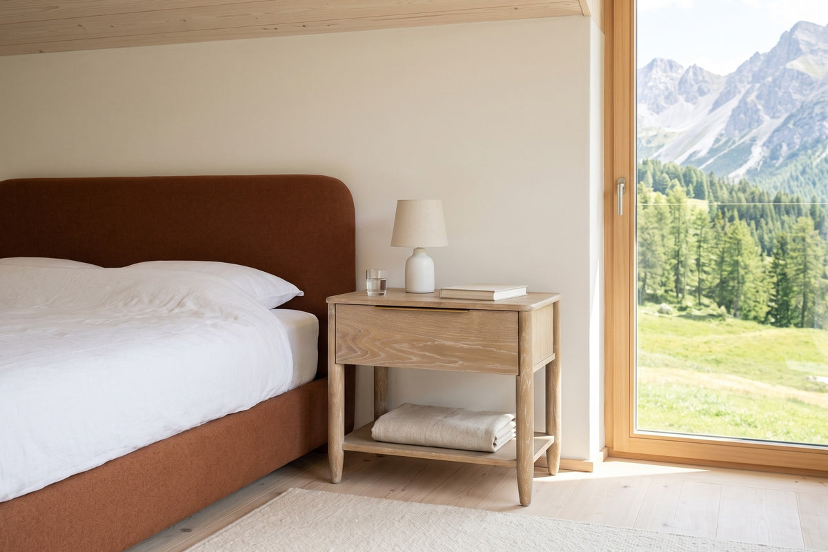 Sarnano nightstand in Sand oak beside a rust wool upholstered bed in a bedroom in an Arosa chalet, with lime plaster