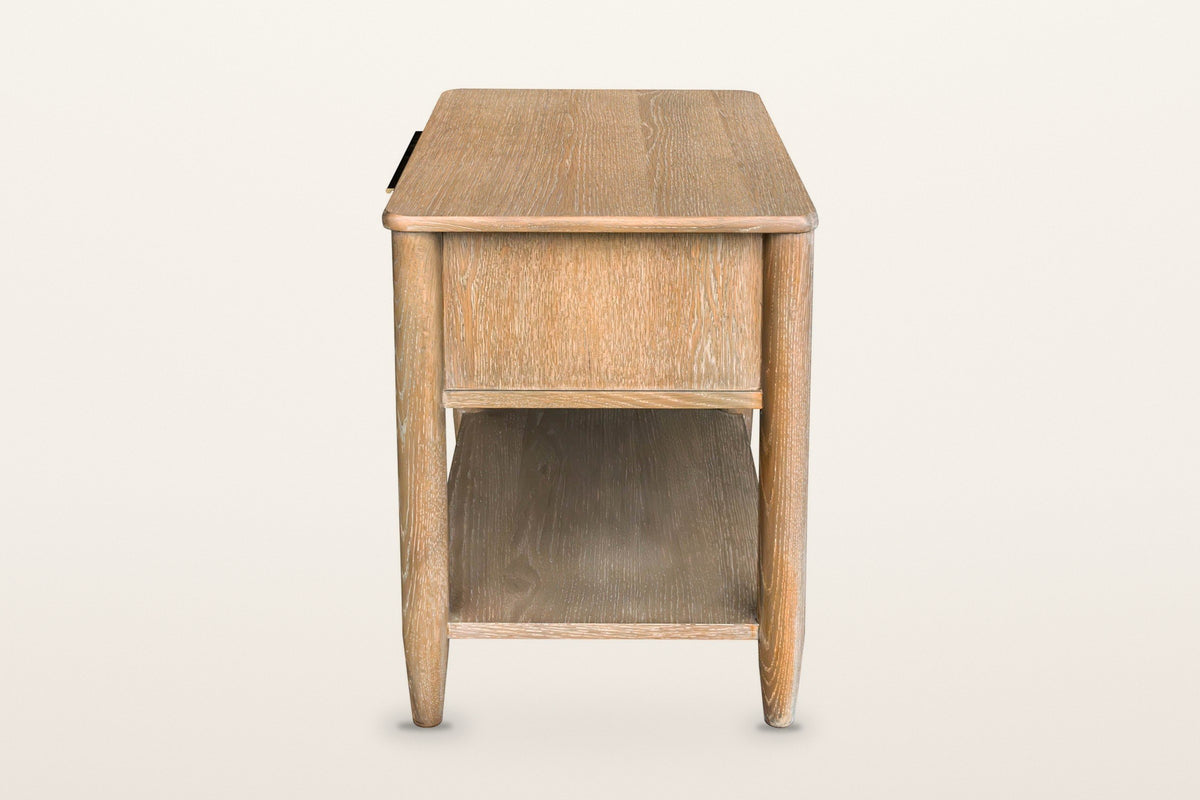 End view of the Sarnano nightstand in Sand on a warm white studio backdrop: the oak side panel under the rounded top