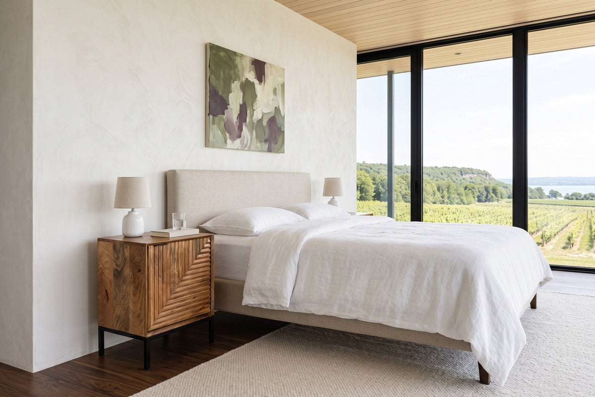 Sarteano nightstand in Pecan mango beside a linen bed in a Beamsville bedroom, with warm white plaster walls