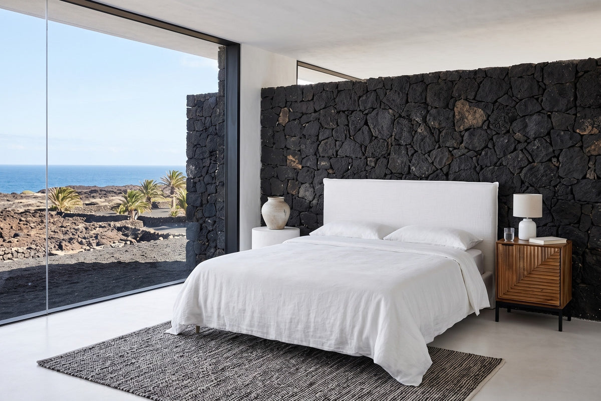 Sarteano nightstand in Pecan mango beside a white linen bed in a Lanzarote bedroom