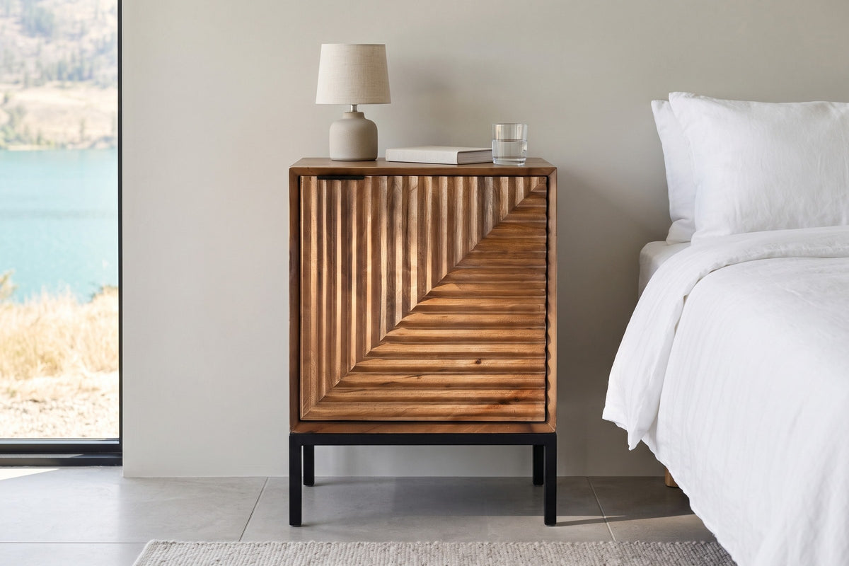 Sarteano nightstand in Pecan mango, front view, beside a white linen bed in a Vernon lakeside bedroom