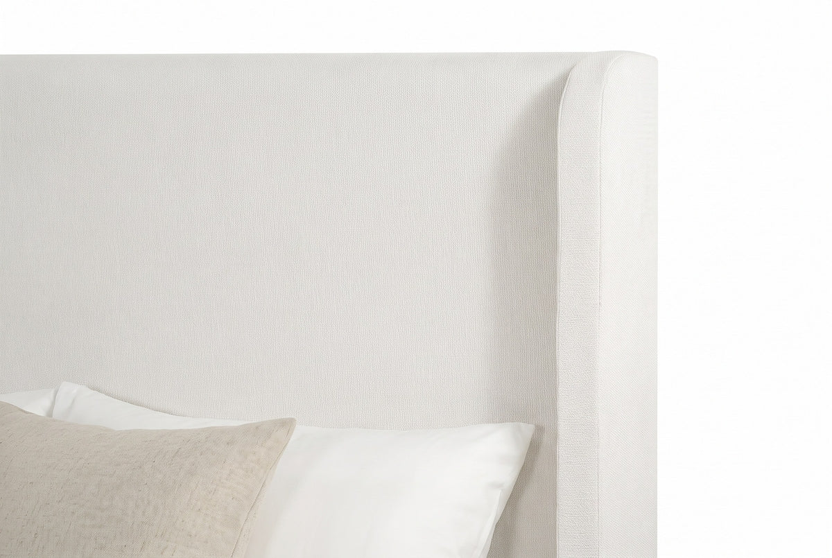 Close-up of the ivory chenille headboard and one slim wing with its rounded top corner