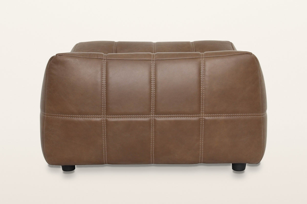 Sassocorvaro ottoman in Antique Sienna from a raised end on a warm white studio backdrop: padded panels in two rows