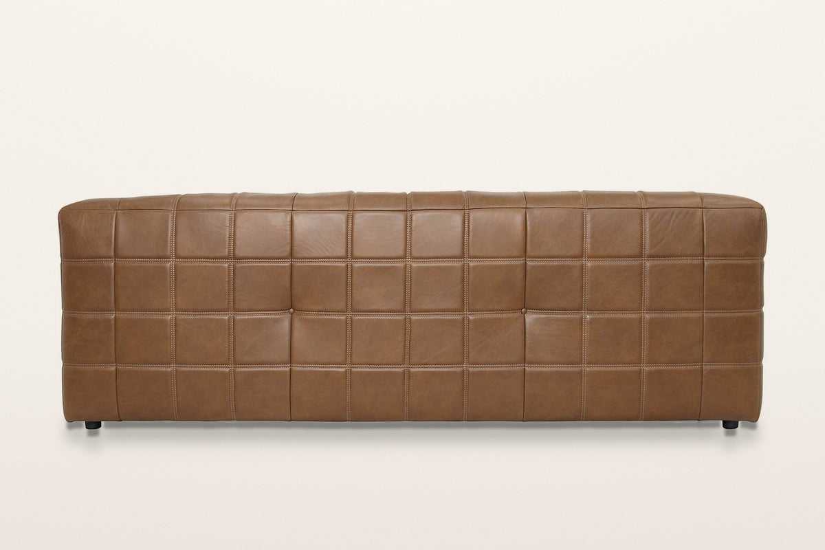 Sassocorvaro sofa in Antique Sienna from behind on a warm white studio backdrop: a plain grid of padded leather squares