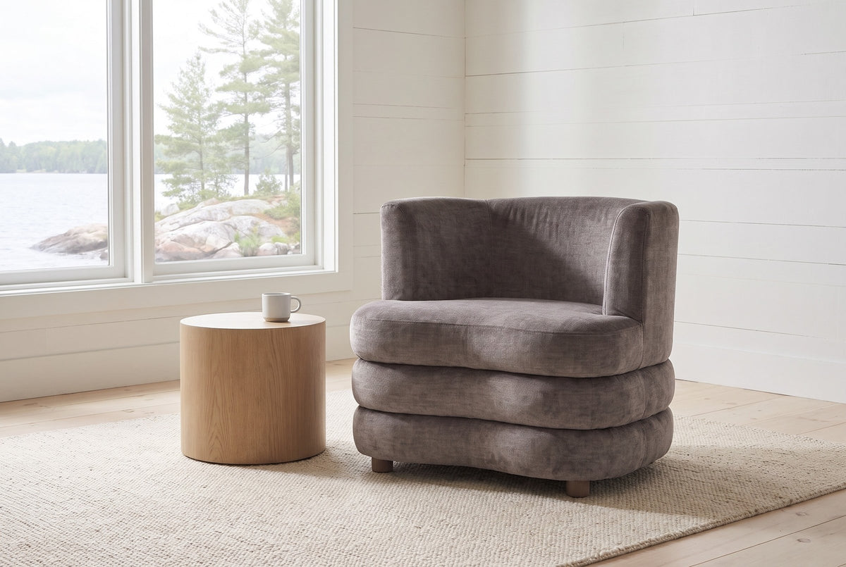 Sauze accent chair in dark taupe velvet, front view, in a white-boarded Muskoka cottage living room, the lake and white pines through the window