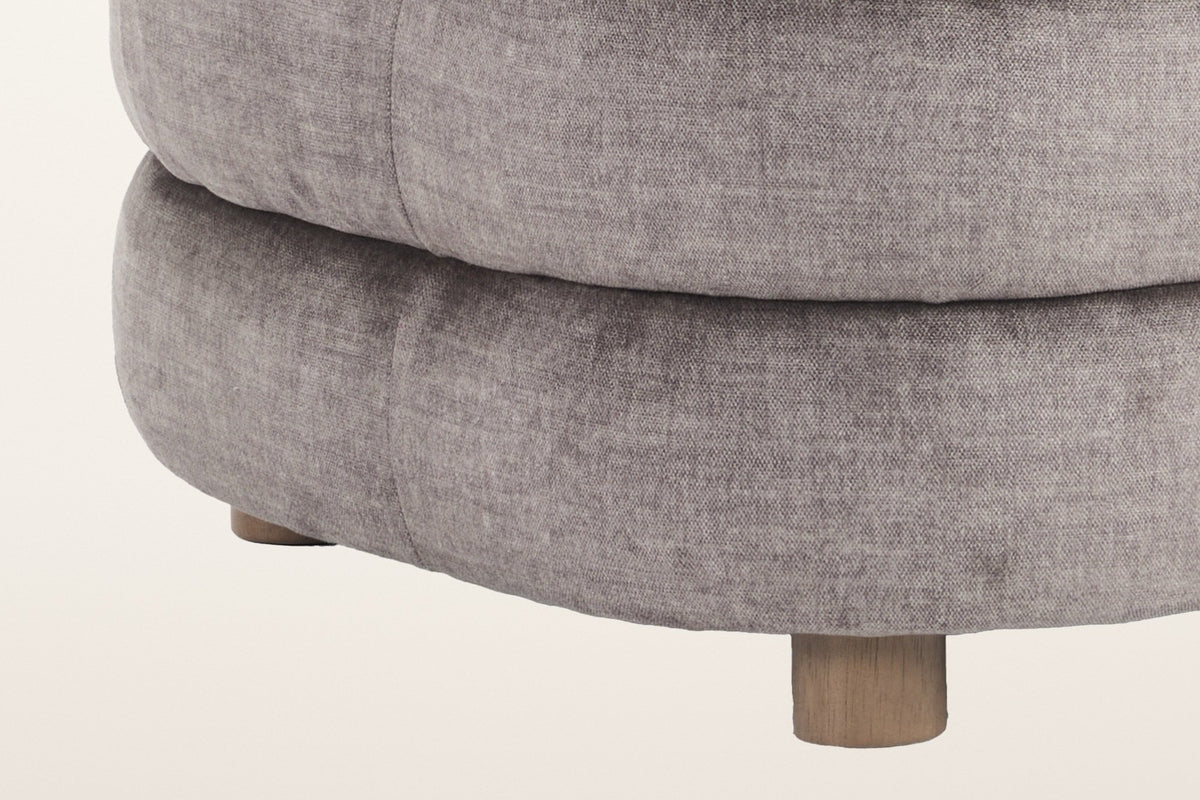 Close-up of the stacked rolls of the Sauze chair in dark taupe velvet and one short round foot