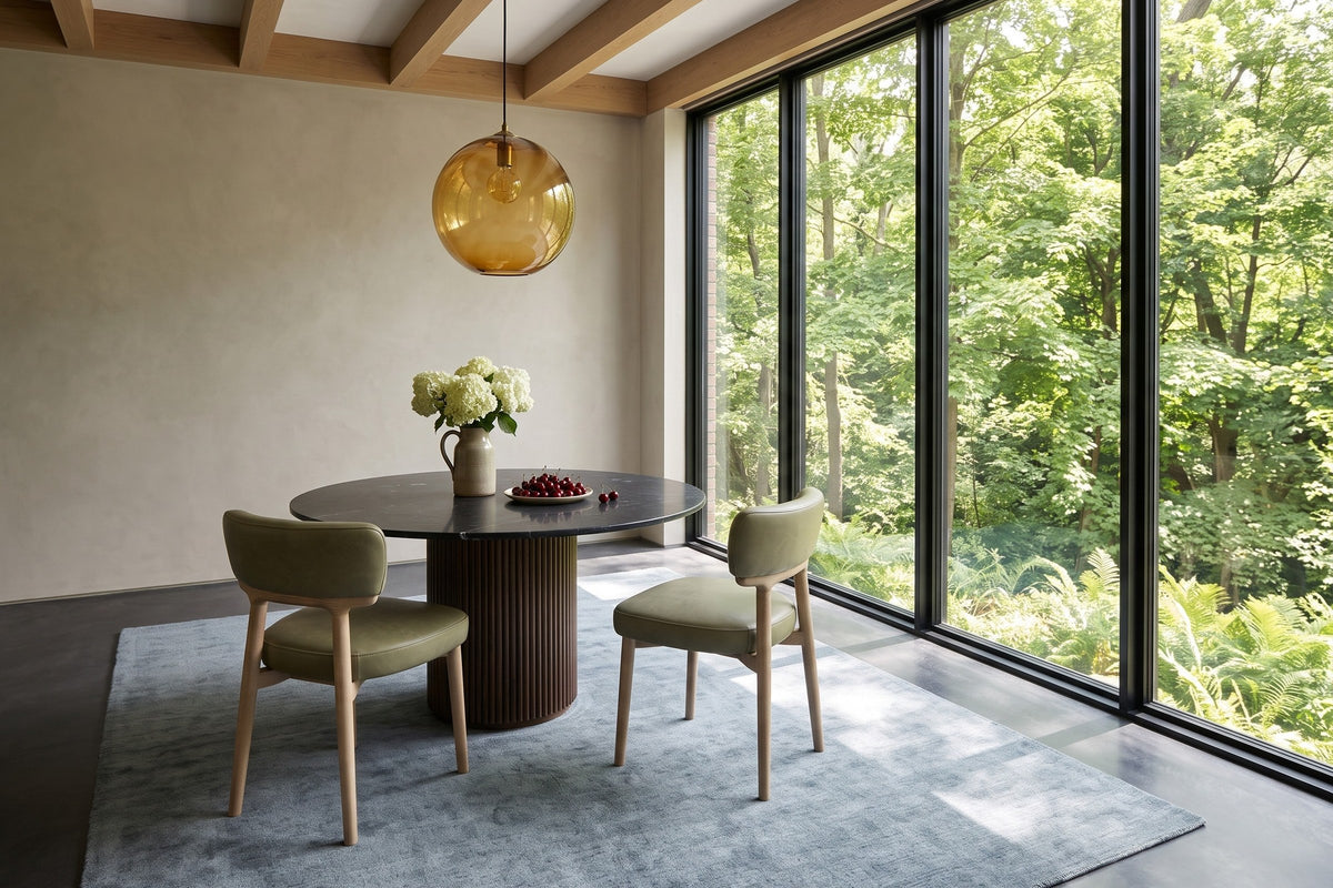 Two Savoca dining chairs in Sage Green leather at a round marble table on a fluted base in a Kleinburg ravine house