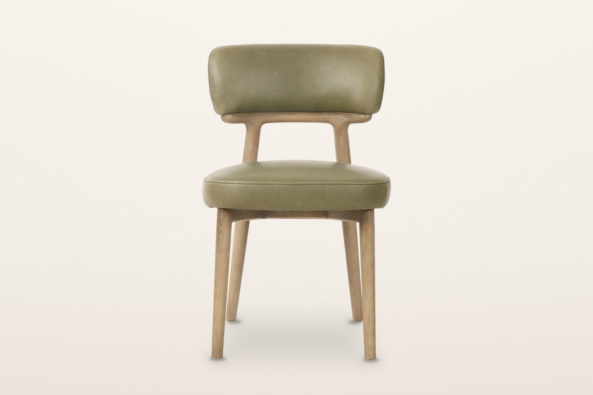 Savoca dining chair in Sage Green leather, front view on a warm white studio backdrop