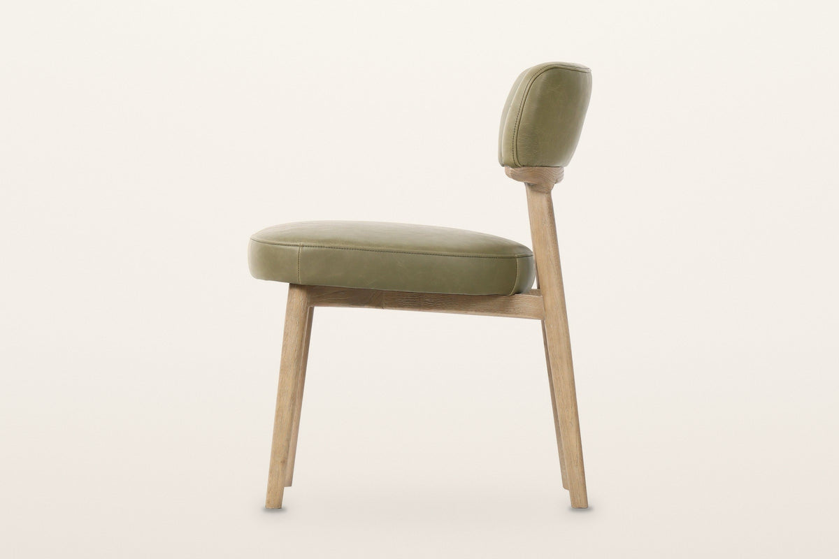 Savoca dining chair in Sage Green leather, side view on a warm white studio backdrop