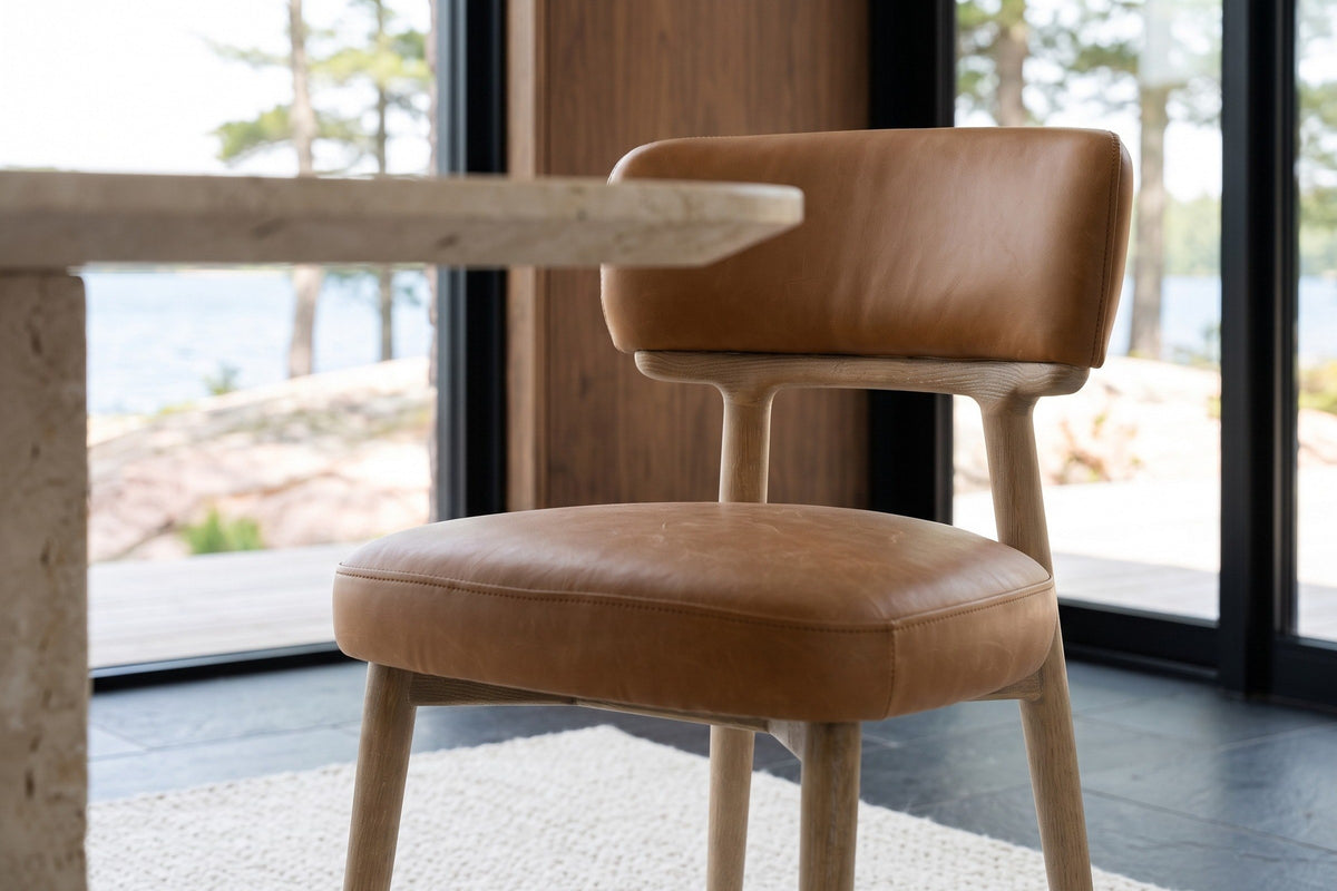 Close-up of a Savoca chair in Tawny leather at seat height: stitched seams on the seat and the back band