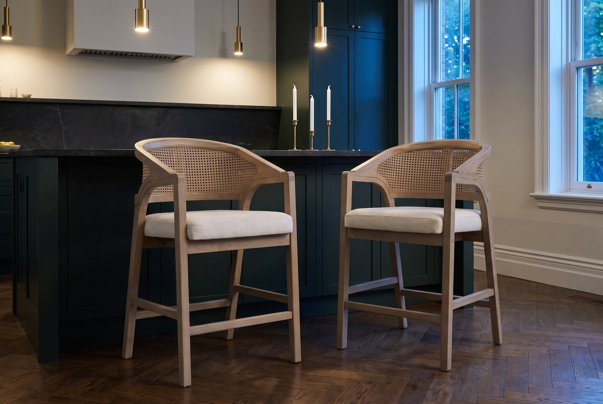 Two Sermoneta counter stools in Natural Ash pulled out from a stone-topped island in a dark green Toronto kitchen at dusk