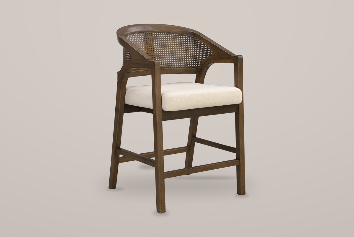 Sermoneta cane-back counter stool in Walnut, front three-quarter view on a warm light-grey studio backdrop