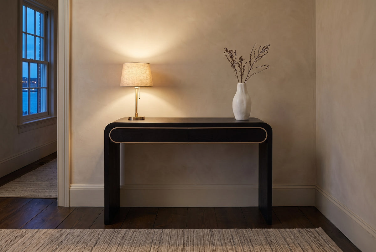 Sestri console table in a limewashed Halifax hallway at dusk, a brass lamp lit and dried branches in a white vase