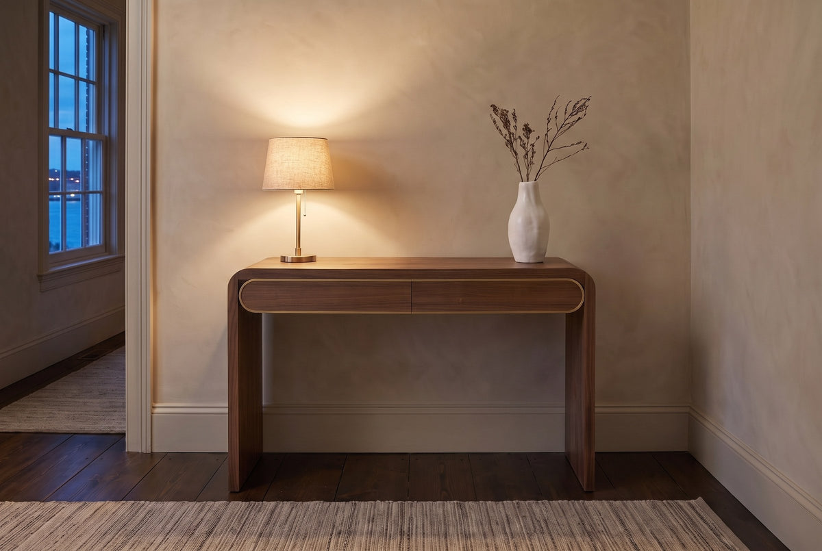 Sestri console table in walnut in a limewashed Halifax hallway at dusk, a brass lamp lit and dried branches in a white vase
