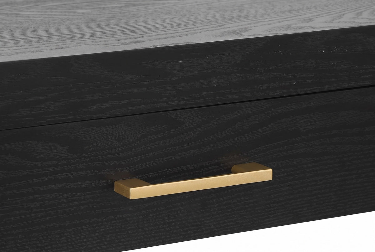 Close-up of a black drawer front with its gold-tone bar pull under the thick top edge