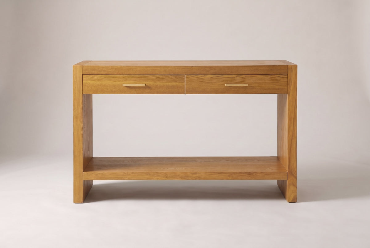 Sibari console table in Natural, straight front view: two drawers with gold-tone pulls, slab sides and a low shelf