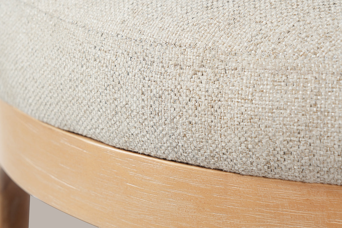 Close-up of the beige linen-blend seat with its seam round the top edge and the brushed wood ring under it