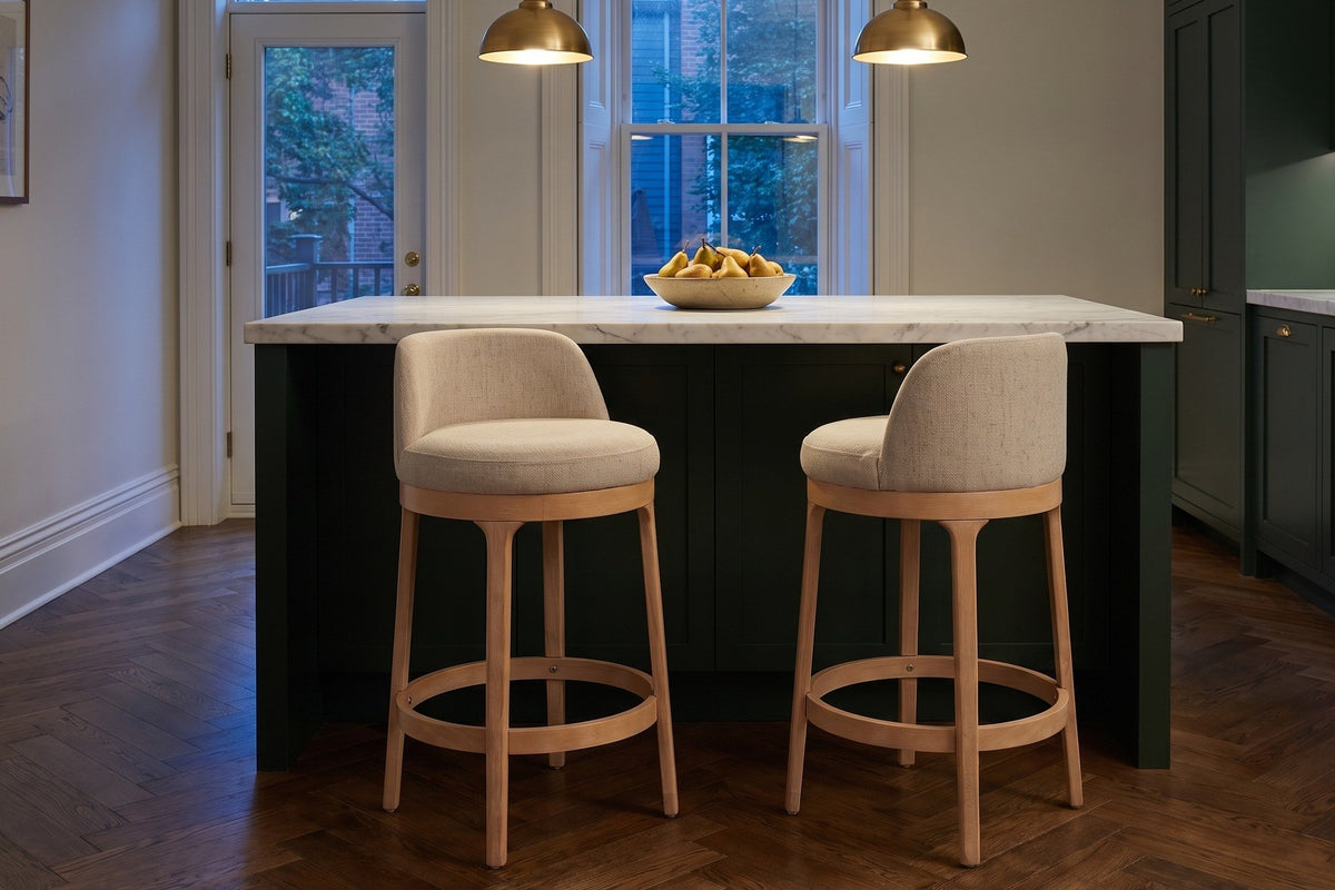 Two Sirolo counter stools at a deep green island with a marble top under brass pendant lamps in a Toronto townhouse kitchen