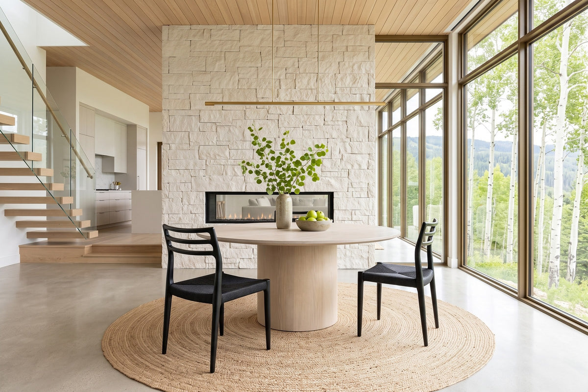Two Sperlinga dining chairs in black at a round limed-oak table in a Sun Peaks mountain house, with a pale stone wall