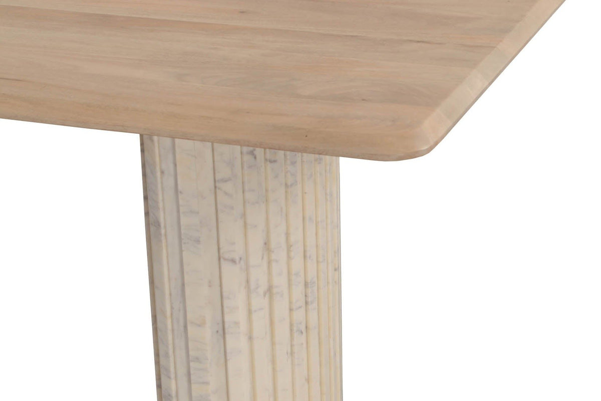 Close-up of a Staffolo corner in Natural: the clipped corner of the mango top over a reeded white marble pedestal