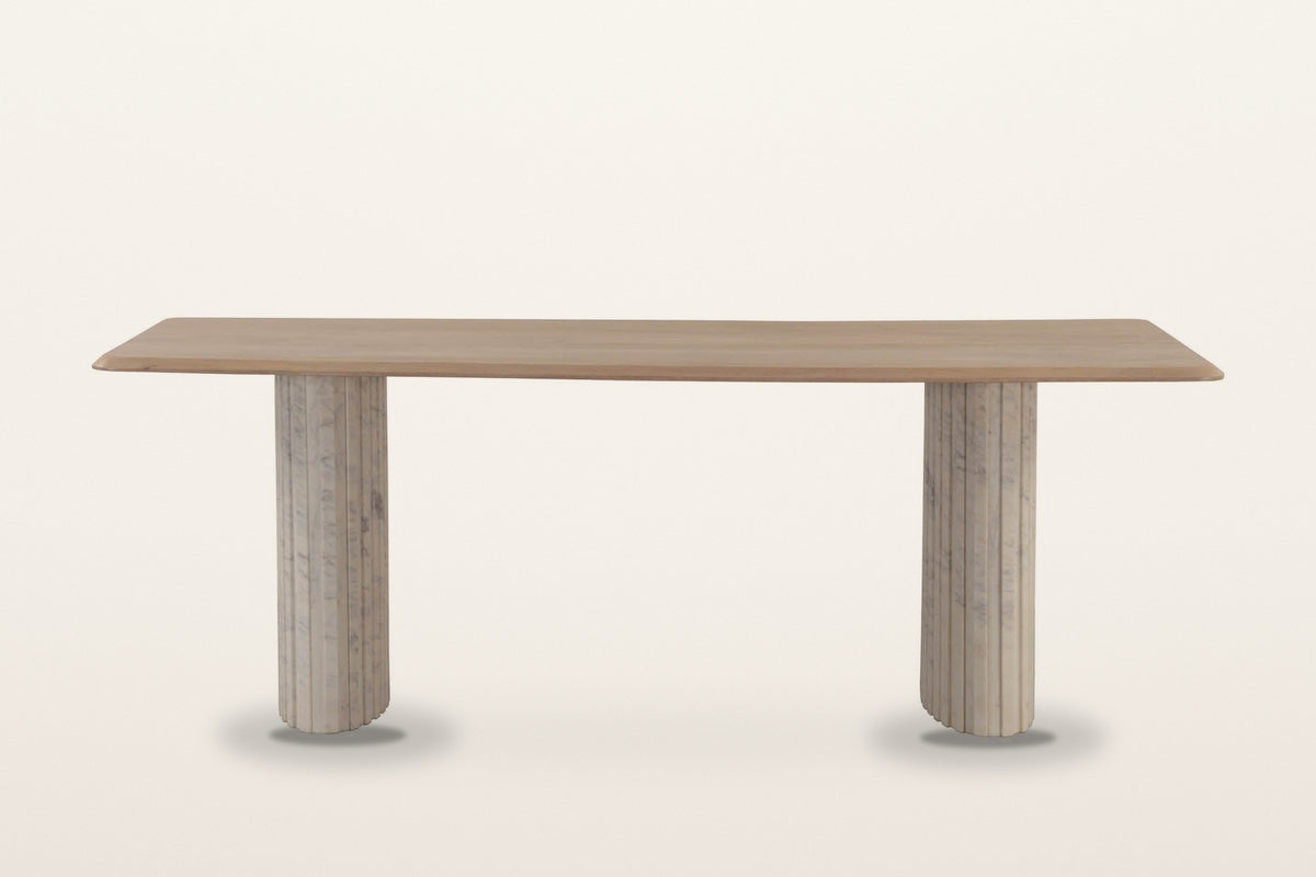 Staffolo dining table in Natural, straight front view on a warm white studio backdrop: a long mango top on two reeded marble