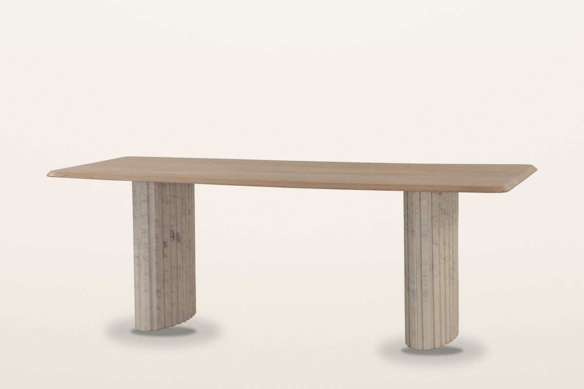 Staffolo marble pedestal dining table in Natural, three-quarter view on a warm white studio backdrop