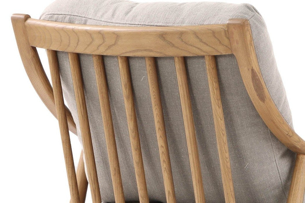 Close-up of the Tagliacozzo back from behind: ash spindles under the curved top rail, the Light Linen cushions behind