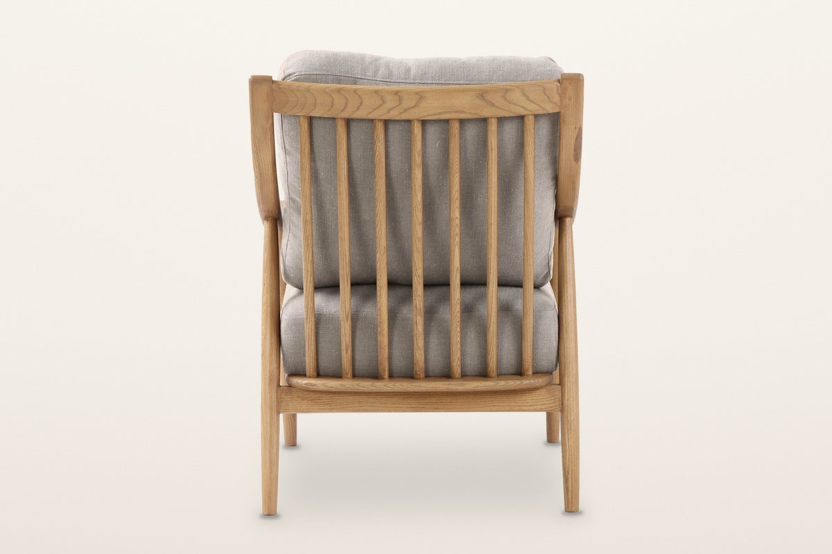 Tagliacozzo accent chair from behind on a warm white studio backdrop: seven ash spindles and the back cushion
