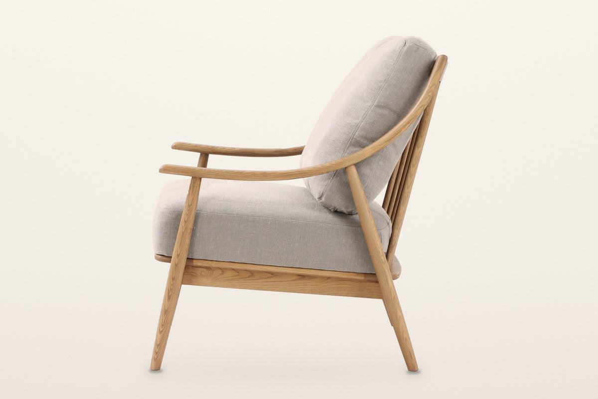 Tagliacozzo accent chair from the side on a warm white studio backdrop: the arm sweeping up into the back post