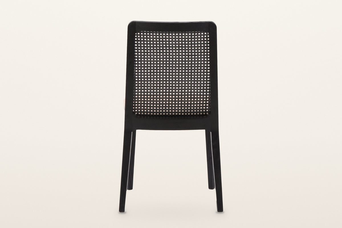 Teggiano dining chair in Black from behind on a warm white studio backdrop: the woven cane panel in its black ash frame