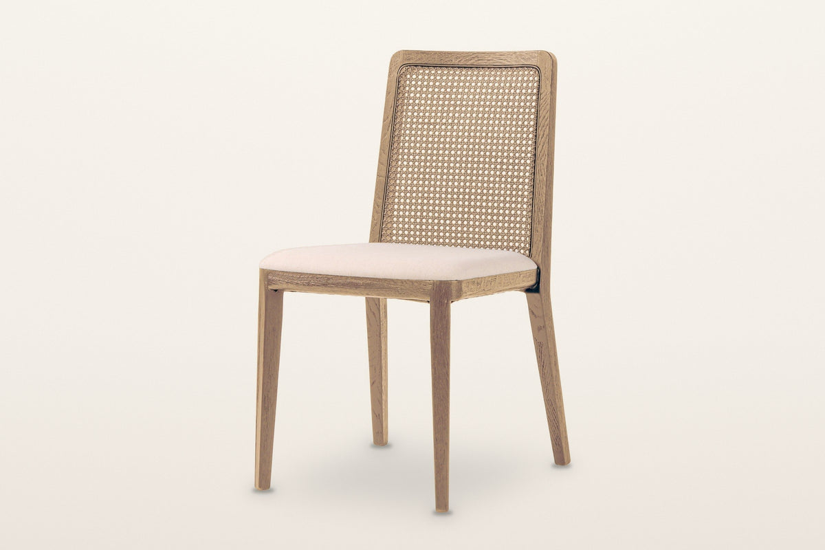 Teggiano cane back dining chair in Natural with an Oyster Linen seat, three-quarter view on a warm white studio backdrop