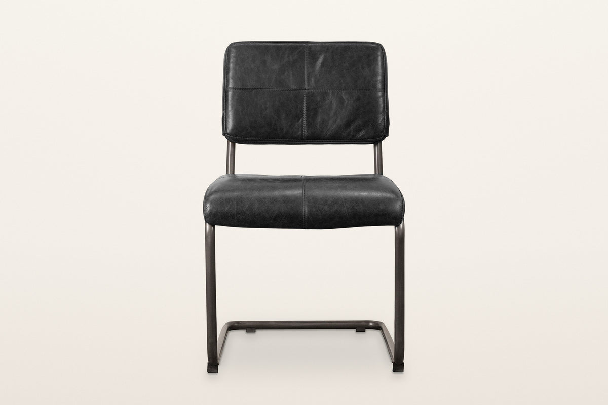 Tenno dining chair in Black, front view on a warm white studio backdrop: the back stitched in four panels and the thick seat