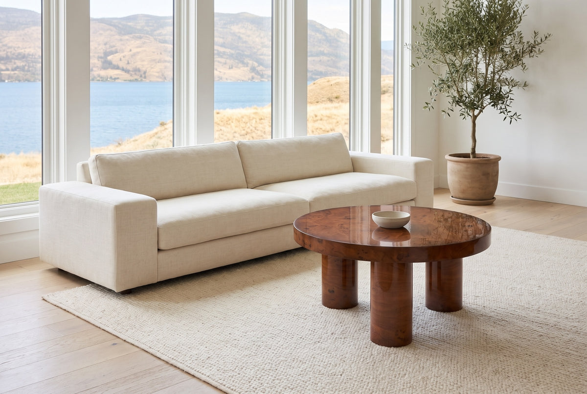 Teramo coffee table on a cream wool rug in front of a linen sofa in a Kelowna lake house, the lake through tall windows