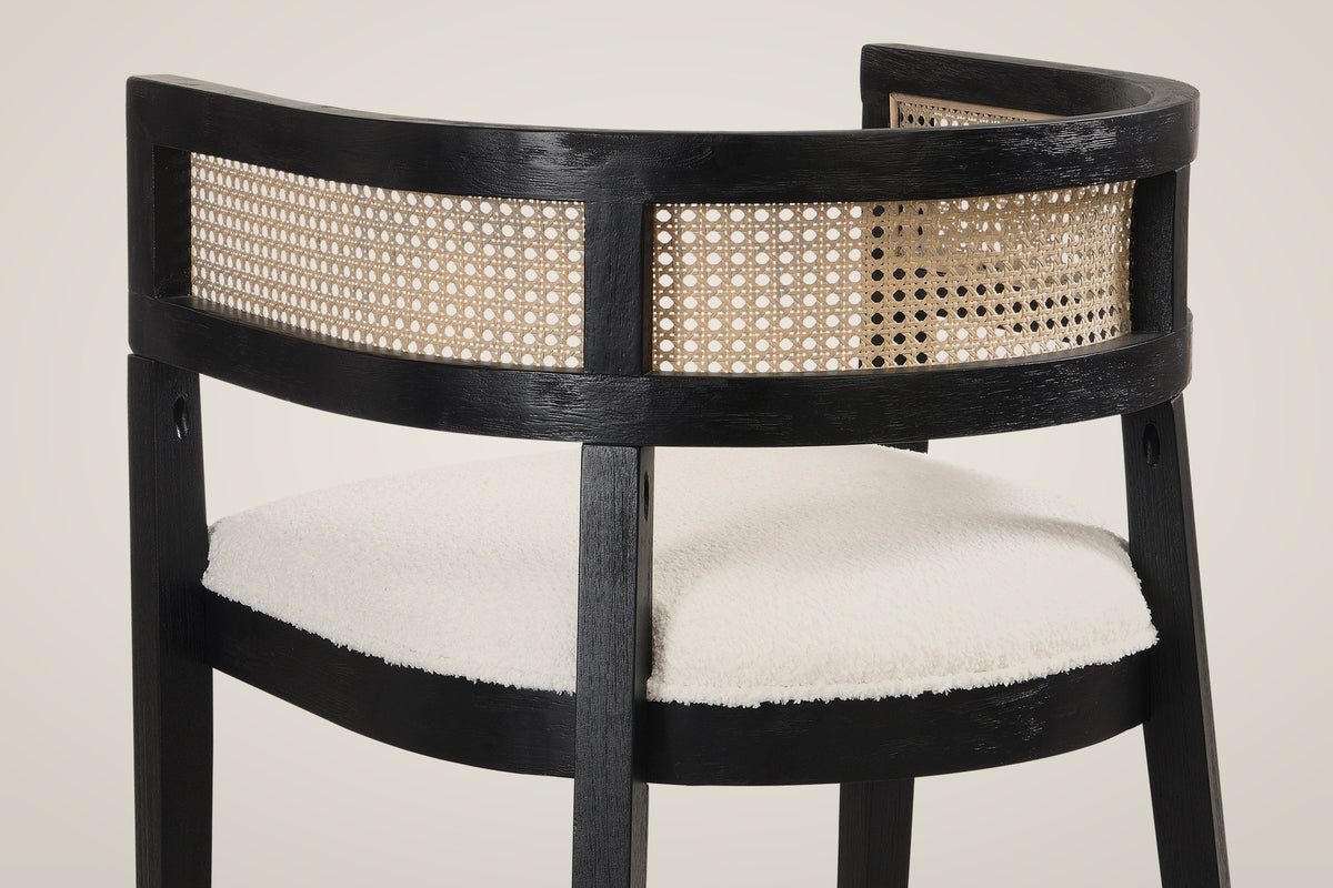 Close-up of the back of a Tolmezzo chair: the black wood rails, the woven cane-look band and the ivory boucle-look seat