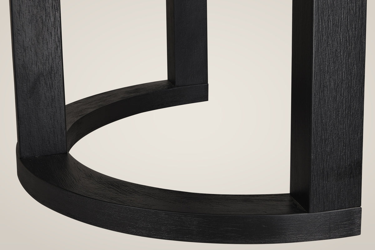 Close-up of one Tolmezzo table base: square black posts standing on a curved half-moon foot, with the open wood grain showing