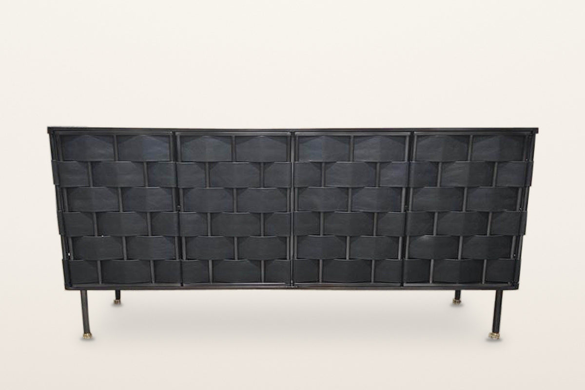 Trequanda sideboard in Black, straight front view on a warm white studio backdrop: four doors woven in black leather straps o