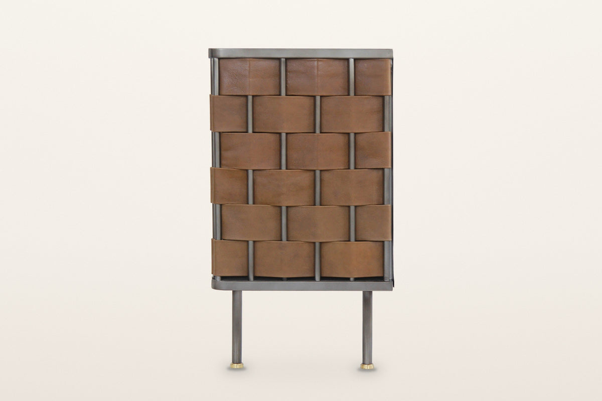The end of the Trequanda sideboard in Brown on a warm white studio backdrop: the same leather weave as the doors