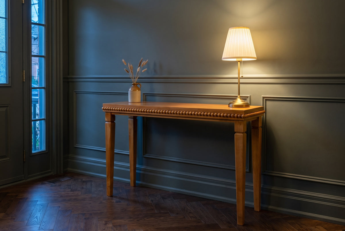 Treviso console table in a green-grey panelled Toronto front hall in the evening, a brass lamp lit at one end