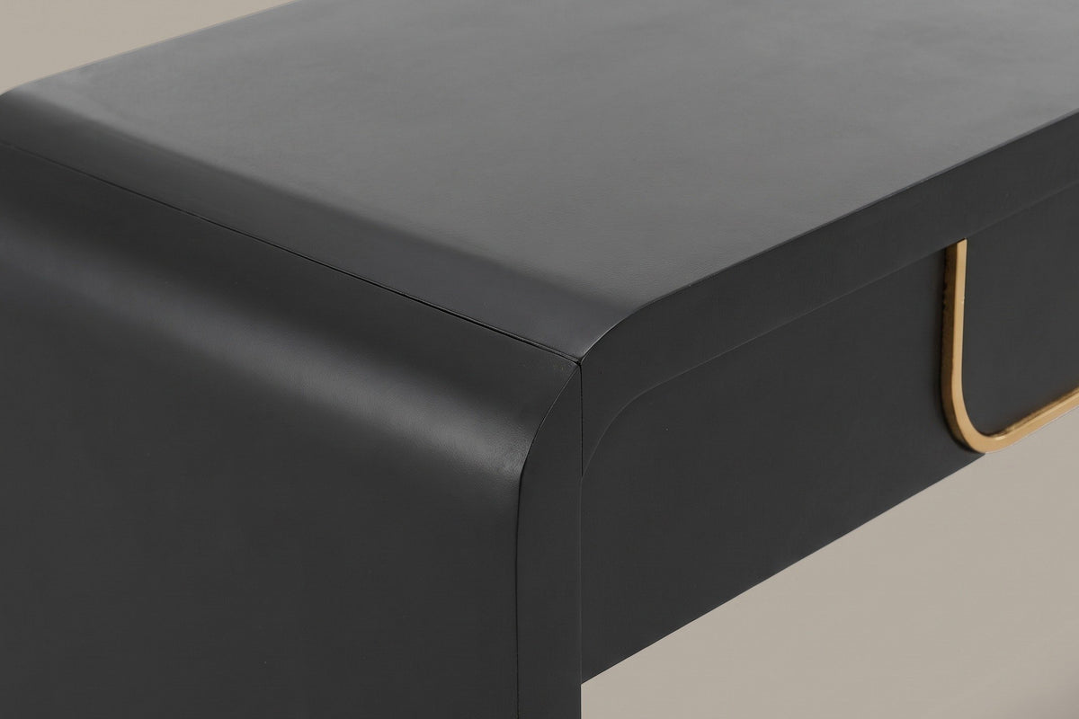 Close-up of the matte black top turning down through a soft rounded bend into the slab leg, the apron set back below it